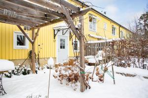 een geel huis met sneeuw ervoor bij Retro Retreat with Modern Comforts in Stockholm