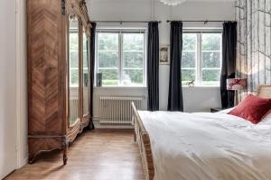 een slaapkamer met een groot bed en 2 ramen bij Historic lakeside villa - ski, boat, relax in nature in Sunnansjö