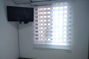 a window with blinds in a room with a television at GURUS FR | Apartamento Central Cerca al estadio y aeropuerto in Pereira