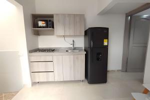 a kitchen with a black refrigerator in a room at GURUS FR | Apartamento Central Cerca al estadio y aeropuerto in Pereira