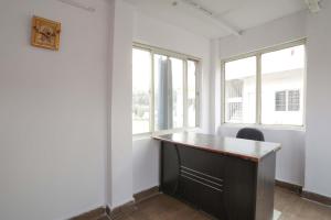 an empty office with a desk and two windows at OYO Hotel Shahnai Garden in Bhopal