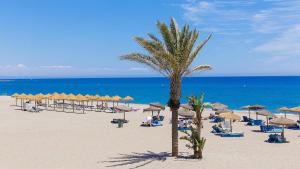 a beach with a lot of chairs and umbrellas at Oasis 4 - Mojacar - Sleeps 4 in Mojácar