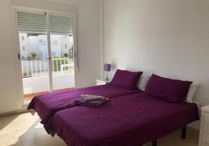 Cama morada en habitación blanca con ventana en Oasis 4 - Mojacar - Sleeps 4 en Mojácar