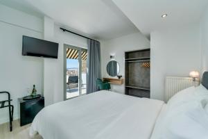 a white bedroom with a large bed and a window at Hotel Adonis Athens in Athens