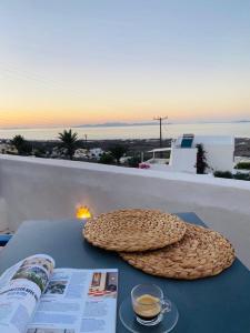a table with a book and a cup of coffee and a newspaper at Palm Tree Hill in Oia