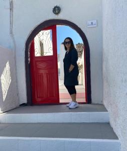 a woman standing in front of a red door at Palm Tree Hill in Oia