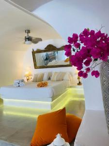 um quarto com uma cama e um vaso com flores roxas em Palm Tree Hill em Oia