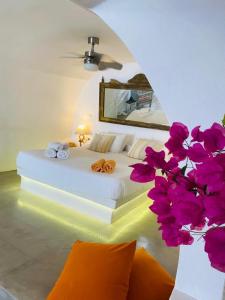 1 dormitorio con 1 cama con espejo y flores en Palm Tree Hill en Oia