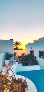 a resort with a pool with a sunset in the background at Palm Tree Hill in Oia