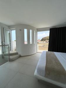 a white bedroom with a bed and a large window at Casa Alcatraz in Puerto Colombia