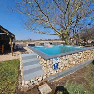 un muro di pietra intorno a una piscina con un muro di pietra di Tamboti Farm Accommodation a Tsumeb