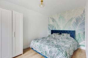 a bedroom with a bed with a blue head board at Appartement Suite aux Portes de Paris in Clichy