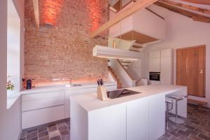 a kitchen with white cabinets and a brick wall at Logies Groot Okhorst in Wichmond
