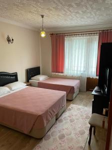 una camera d'albergo con due letti e una televisione di abantgüneşpansiyon a Bolu