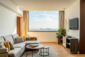 sala de estar con sofá y ventana grande en Torre Melina, a Gran Meliá Hotel, en Barcelona