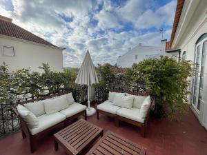 um pátio com 2 sofás, uma mesa e um guarda-chuva em Charming beach house em São Martinho do Porto
