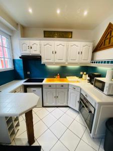 uma cozinha com armários brancos, um lavatório e uma mesa em Villa Garance em Le Tréport