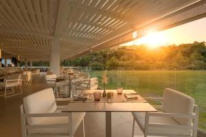 a dining room with a table and chairs and the sunset at Lindos Imperial Resort & Spa in Kiotari