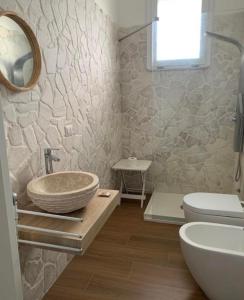 a bathroom with a bowl sink and a toilet at Villa Clemente in Marina di Lizzano