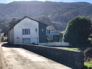 a small white building on a road next to a mountain at Maison Bois in Laruns