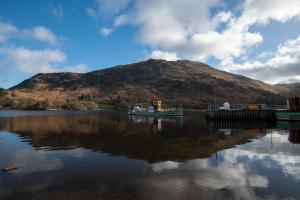 a reflection of a mountain in a body of water at The Ullswater Inn- The Inn Collection Group in Glenridding