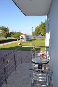 balcón con mesa, sillas y vistas al océano en Akrogiali studios, en Vasilika