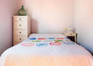 uma cama com uma colcha branca com rosas coloridas em Casa de playa TABI Caión- A Coruña (VUT-CO-000899) em Cayón