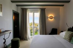 a bedroom with a bed and a large window at Donna Carmela Resort & Lodges in Riposto