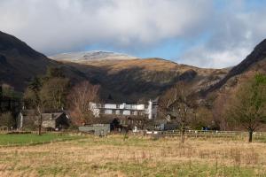 a house in a field in front of a mountain at The Ullswater Inn- The Inn Collection Group in Glenridding