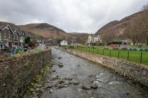 a river in a town with mountains in the background at The Ullswater Inn- The Inn Collection Group in Glenridding