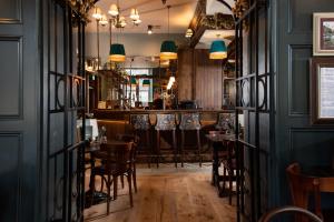 a dining room with a bar with wooden tables and chairs at The Ullswater Inn- The Inn Collection Group in Glenridding