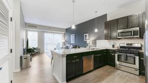 una cocina con armarios negros y electrodomésticos de acero inoxidable en Landing Modern Apartment with Amazing Amenities (ID4080X59) en Minnetonka