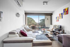 a living room with a couch and a table at VERT PARADIS - Vue apaisante sur GOLF, Pins Parasols, 2è étage - 80 m2 dont Terrasse avec Pergola, 2 chambres, 3ét iles, 3 CLIM, WIFI - Piscine, Parking et Park à vélos, Ascenseur - en Option Linge, Ménage - Pistes cyclables, Mer à proximité in Saint-Cyprien