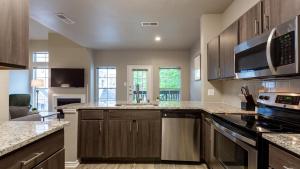 a kitchen with wooden cabinets and a stove top oven at Landing Modern Apartment with Amazing Amenities (ID4600X56) in Irving