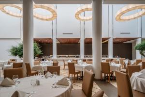 a restaurant with white tables and chairs and chandeliers at Lindos Royal Resort in Líndos