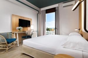 a bedroom with a bed and a desk and a window at UNAHOTELS Naxos Beach Sicilia in Giardini Naxos