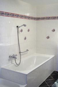 a white bath tub with a shower in a bathroom at Ferienwohnung Kottmarsdorf in Kottmarsdorf