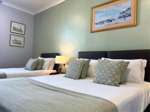a bedroom with two beds and a picture on the wall at The Windmill Hotel - Alford in Alford