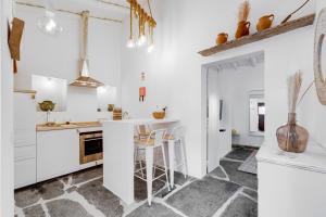 a kitchen with white cabinets and a counter with stools at Casa da Junqueira - Lago do Alqueva in Campinho