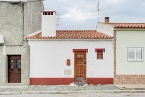 een wit gebouw met een rode en witte deur bij Casa da Junqueira - Lago do Alqueva in Campinho
