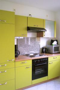 a kitchen with yellow cabinets and a black oven at Ferienwohnung Kottmarsdorf in Kottmarsdorf