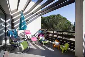 a group of chairs and an umbrella on a balcony at VERT PARADIS - Vue apaisante sur GOLF, Pins Parasols, 2è étage - 80 m2 dont Terrasse avec Pergola, 2 chambres, 3ét iles, 3 CLIM, WIFI - Piscine, Parking et Park à vélos, Ascenseur - en Option Linge, Ménage - Pistes cyclables, Mer à proximité in Saint-Cyprien