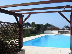 a swimming pool with a wooden pergola next to it at Maisonnette 4 pers- Piscine commune - Plage à 500 m- AESA in Guidel-Plage