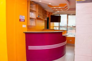 a red counter in an office with yellow and orange walls at Epitome Times Hotel in Nairobi