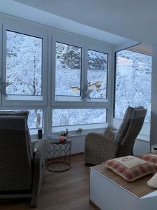 a living room with three windows with snow outside at Nefer, Haus in Bad Gastein