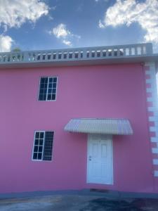 różowy budynek z białymi drzwiami i niebem w obiekcie Three Palm Villa w mieście Montego Bay