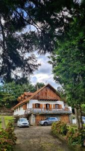 a building with two cars parked in front of it at CASA EM MONTE VERDE-MG ACOMODA 15 PESSOAS in Monte Verde