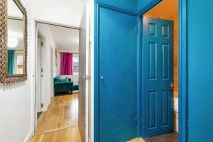 a blue door in a hallway with a mirror at City-Accessible 1-Bed Apartment in Bethnal Green in London