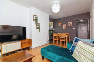 a living room with a couch and a tv and a table at City-Accessible 1-Bed Apartment in Bethnal Green in London