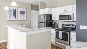 uma cozinha com armários brancos e um forno com placa de fogão em Landing Modern Apartment with Amazing Amenities (ID9437X39) em Fishers